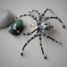 Beaded wire spider featuring a detailed silver-patterned bead, black legs, and shimmering accent beads for a mystical handmade décor piece.